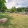 a grassy area with a fence and trees in the background