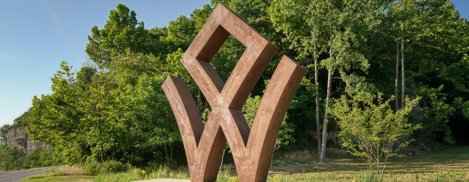 a sculpture of a logo in a grassy area